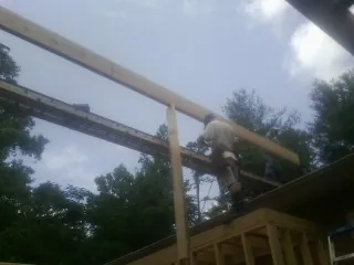 Carpenter setting a ridge beam over a new addition frame — Ice Dam Removal by Roofing Brothers in Newton Grove