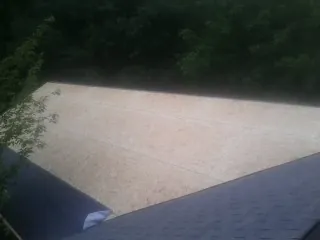 New OSB roof sheathing installed beside an existing shingle roof in Newton Grove