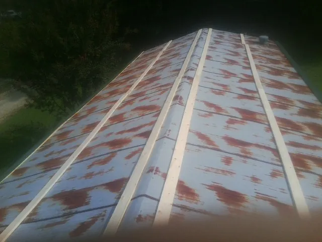 Rusted metal roof panels with new wood purlins before replacement — Storm Damage Roof Repair in Newton Grove by Roofing Brothers