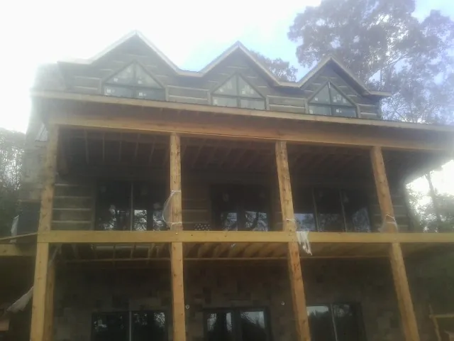 Dormers and porch framing on a large log home under construction — Roof Coating work by our crew in Newton Grove