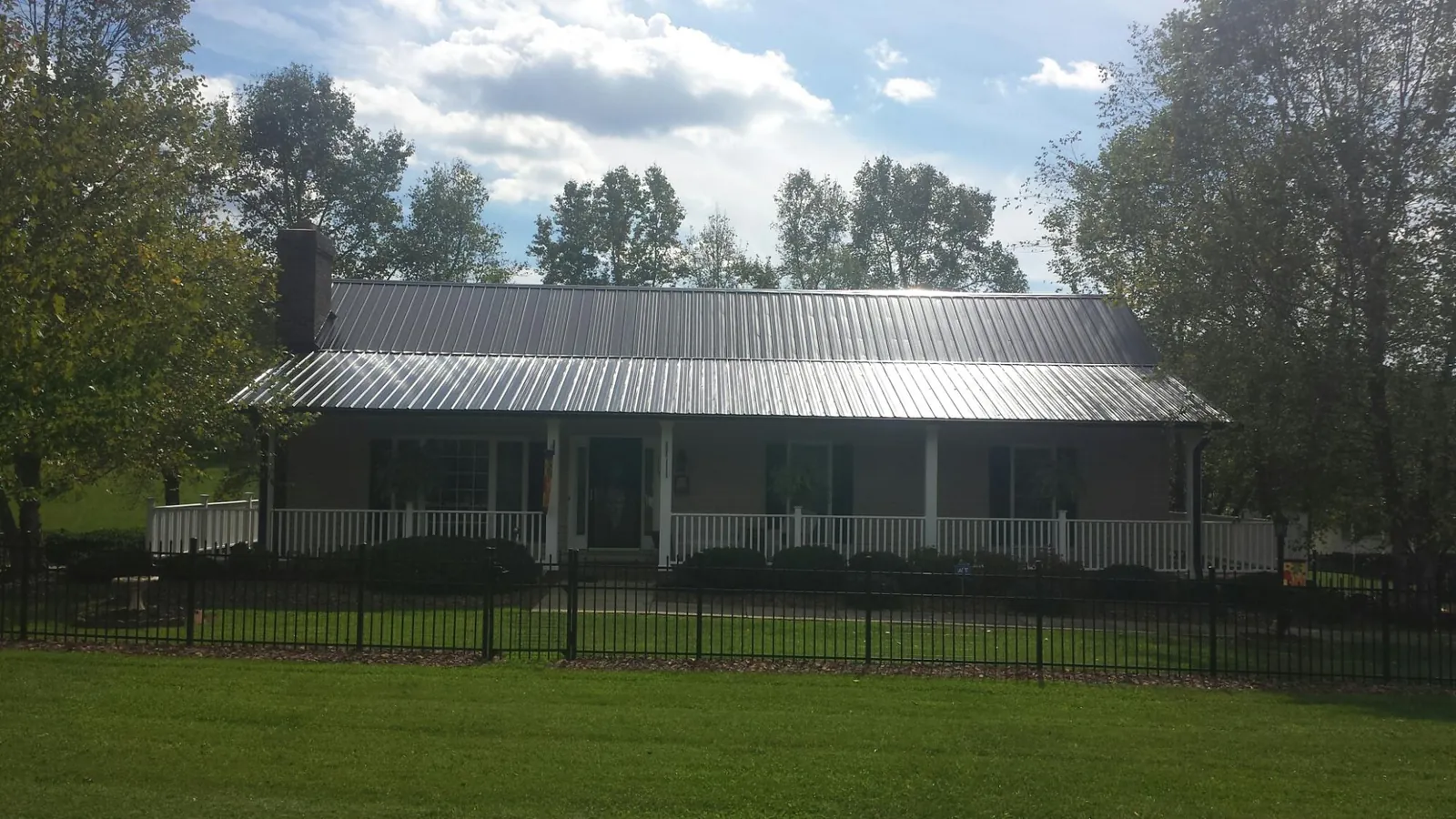 Gray metal roof on a brick ranch with a full width front porch — Gutter Guard Installation work by our crew in Newton Grove