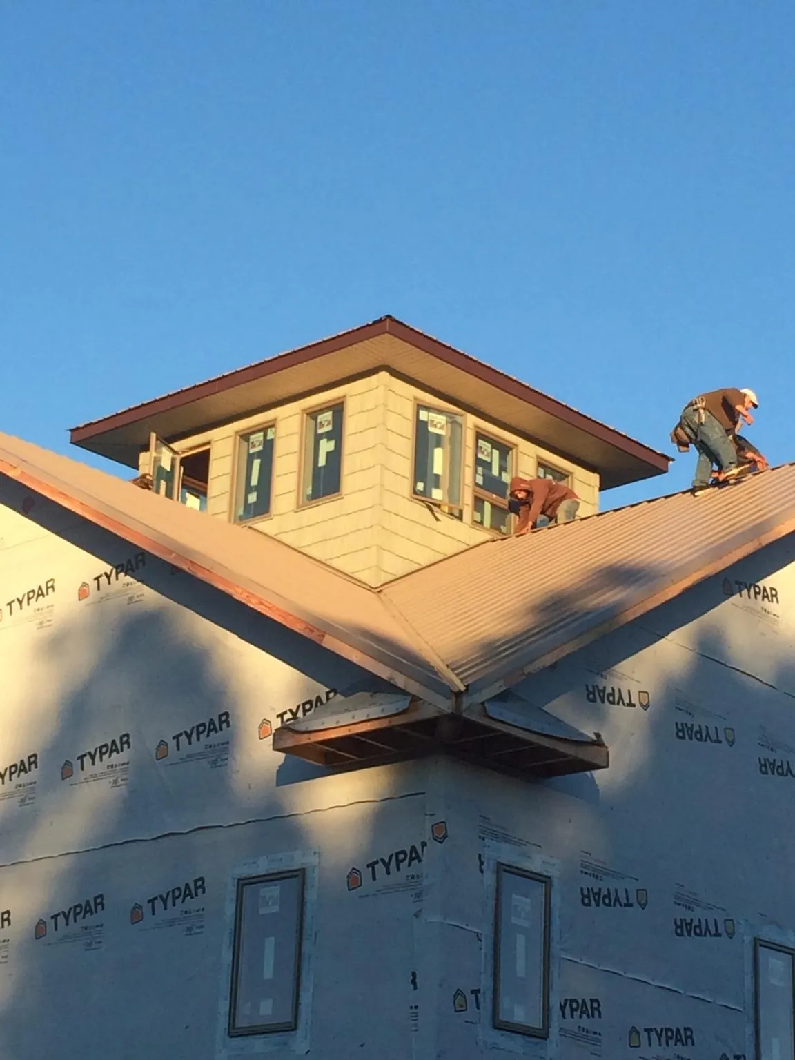 Roofers working around a rooftop cupola on a new metal roof at sunset — Roof Waterproofing in Newton Grove by Roofing Brothers